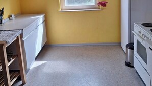 A compact kitchen with a window, a clock, and a refrigerator. - Cozy vacation apartment at the Hainerhof (Grünberg)