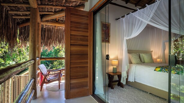 A bedroom with a glass door leading to a balcony, a bed with a canopy, and a wooden ceiling. - Casa Limone (Porto Seguro)