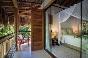 Une chambre avec une porte vitrée donnant sur un balcon, un lit à baldaquin et un plafond en bois.