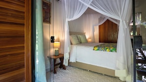 A bedroom with a canopy bed, a bedside table with a lamp, and a view of the outdoors. - Casa Limone (Porto Seguro)