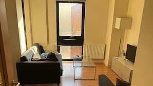 Ein modernes Wohnzimmer mit einer Couch, einem Couchtisch und einem Fernseher.
