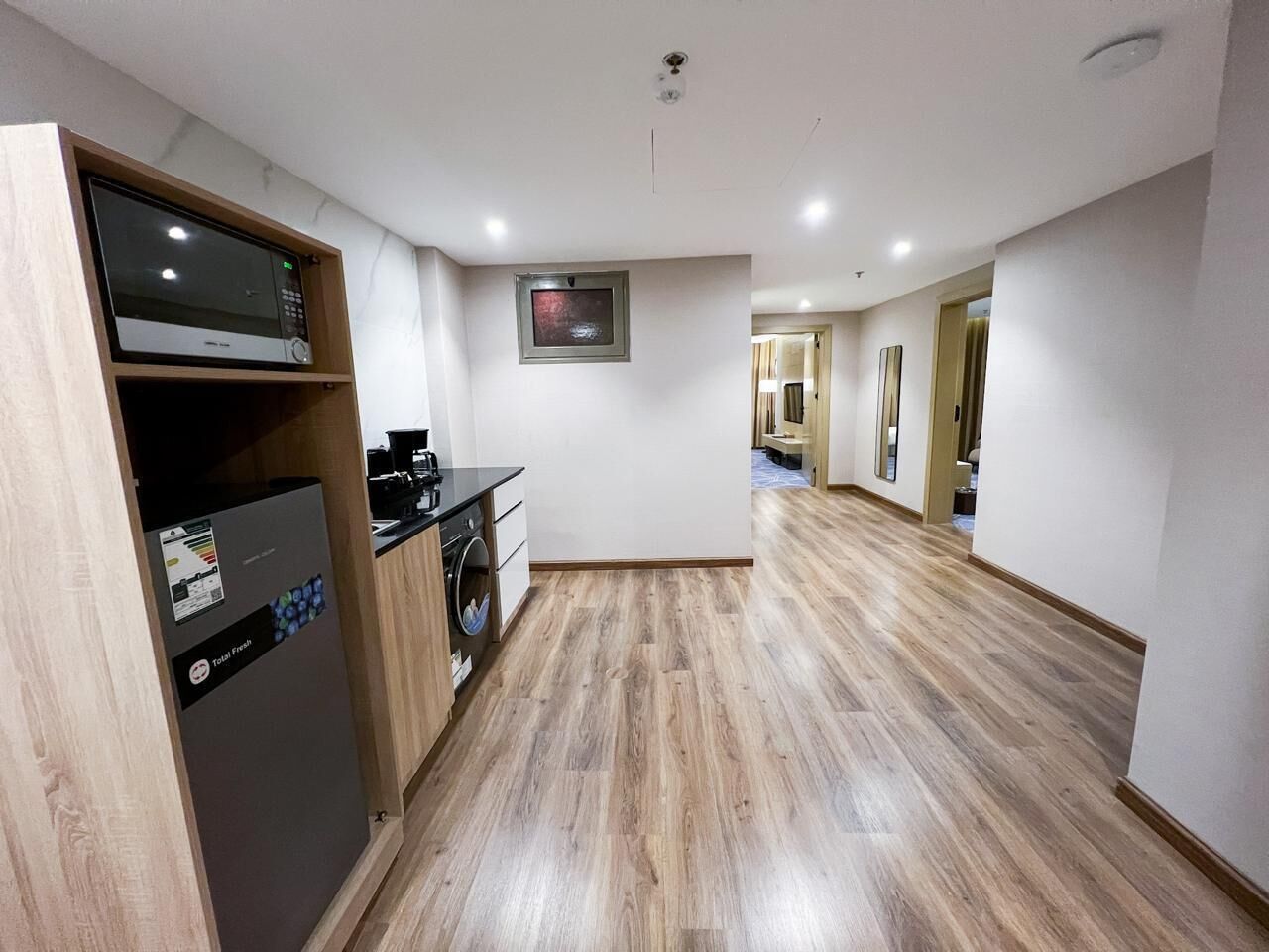 A modern kitchen with a built-in microwave, a coffee machine, and a washing machine.