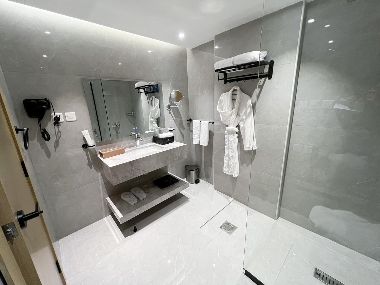 Een moderne badkamer met een douchecabine van glas, een wastafel met spiegel en een handdoekrek.