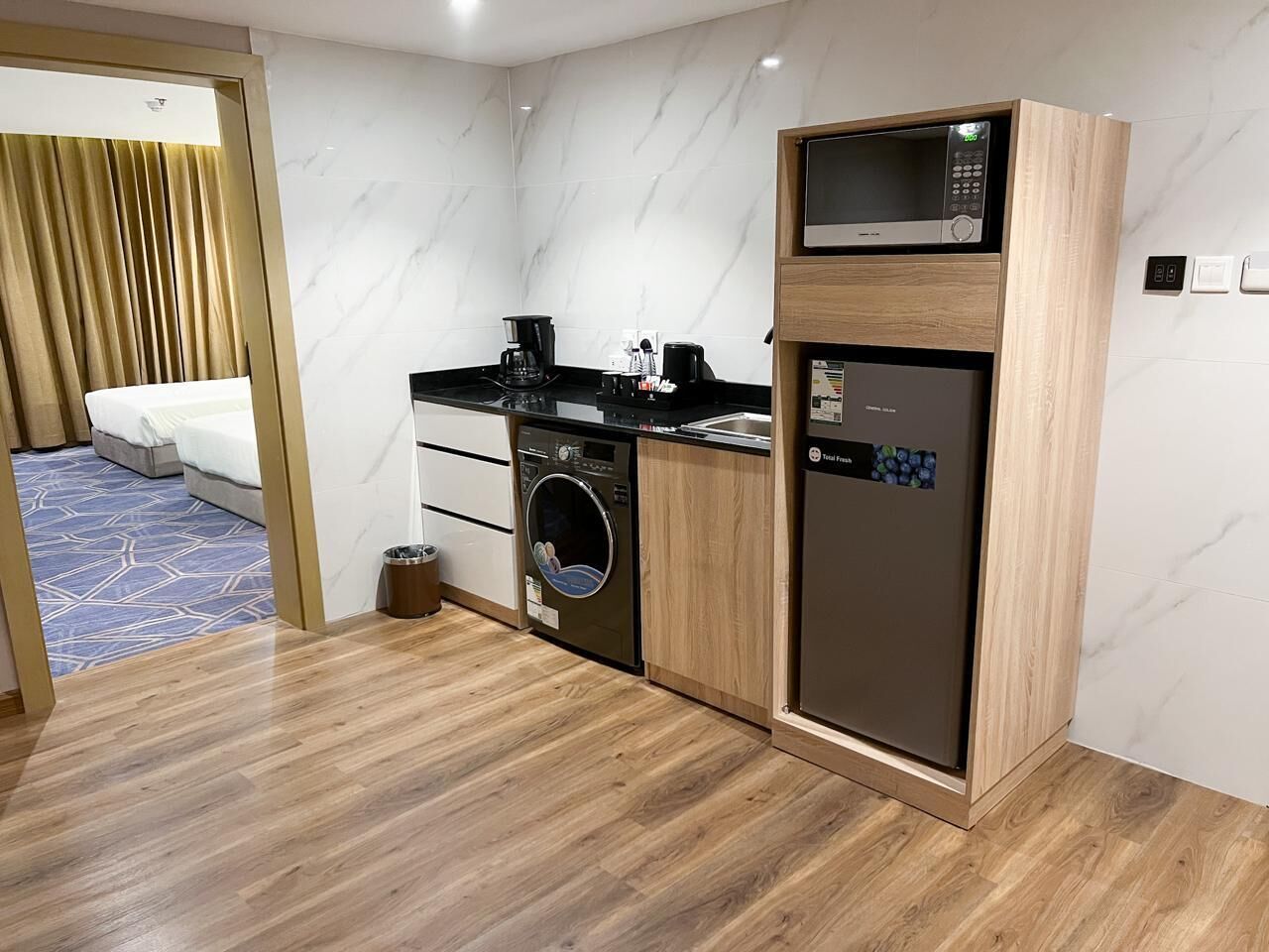 Een compacte hotelkamer met een ingebouwde wasmachine en droger, een magnetron en een kleine koelkast.