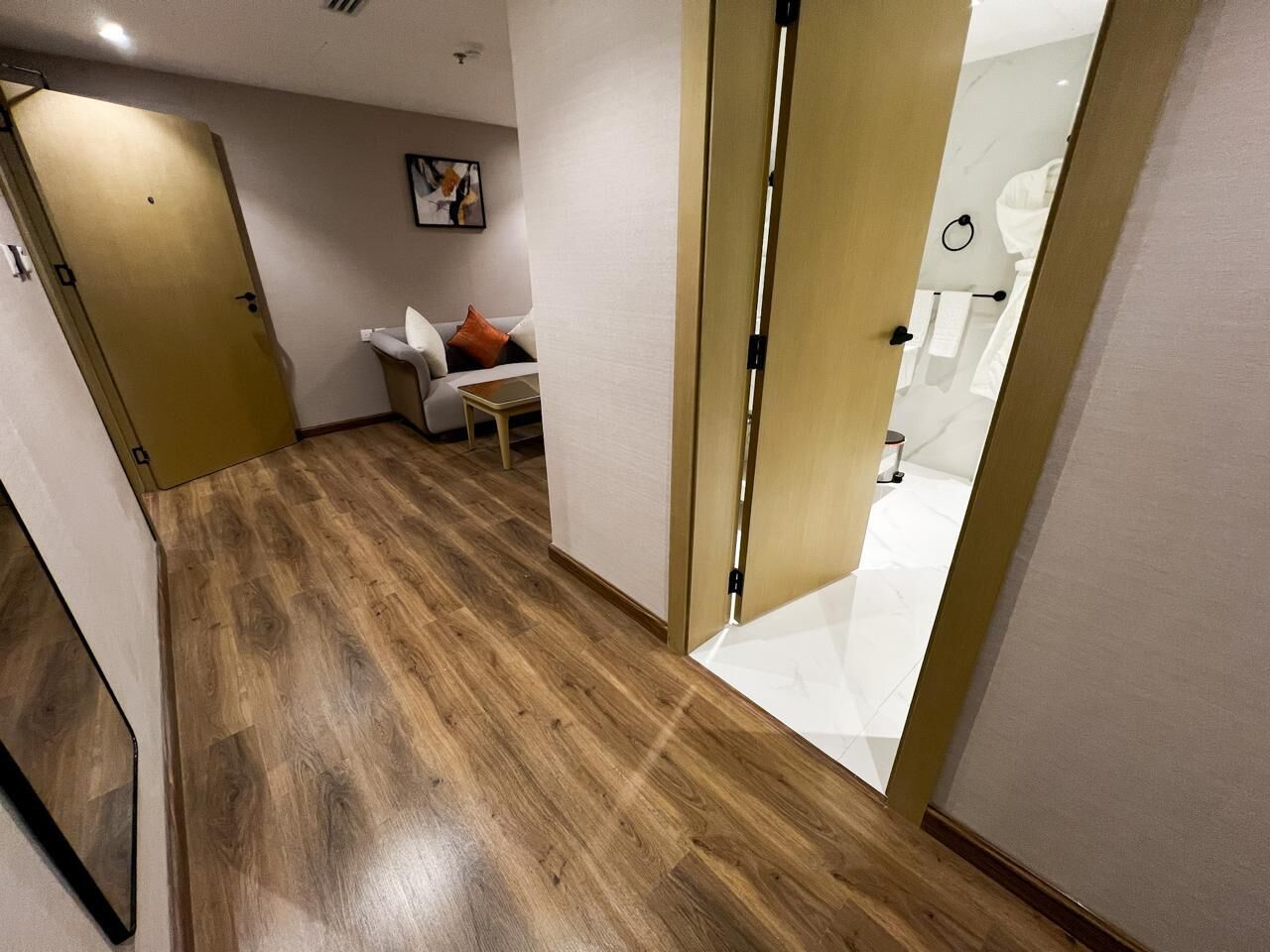 A hallway with wooden flooring, a white sofa, and a small table.