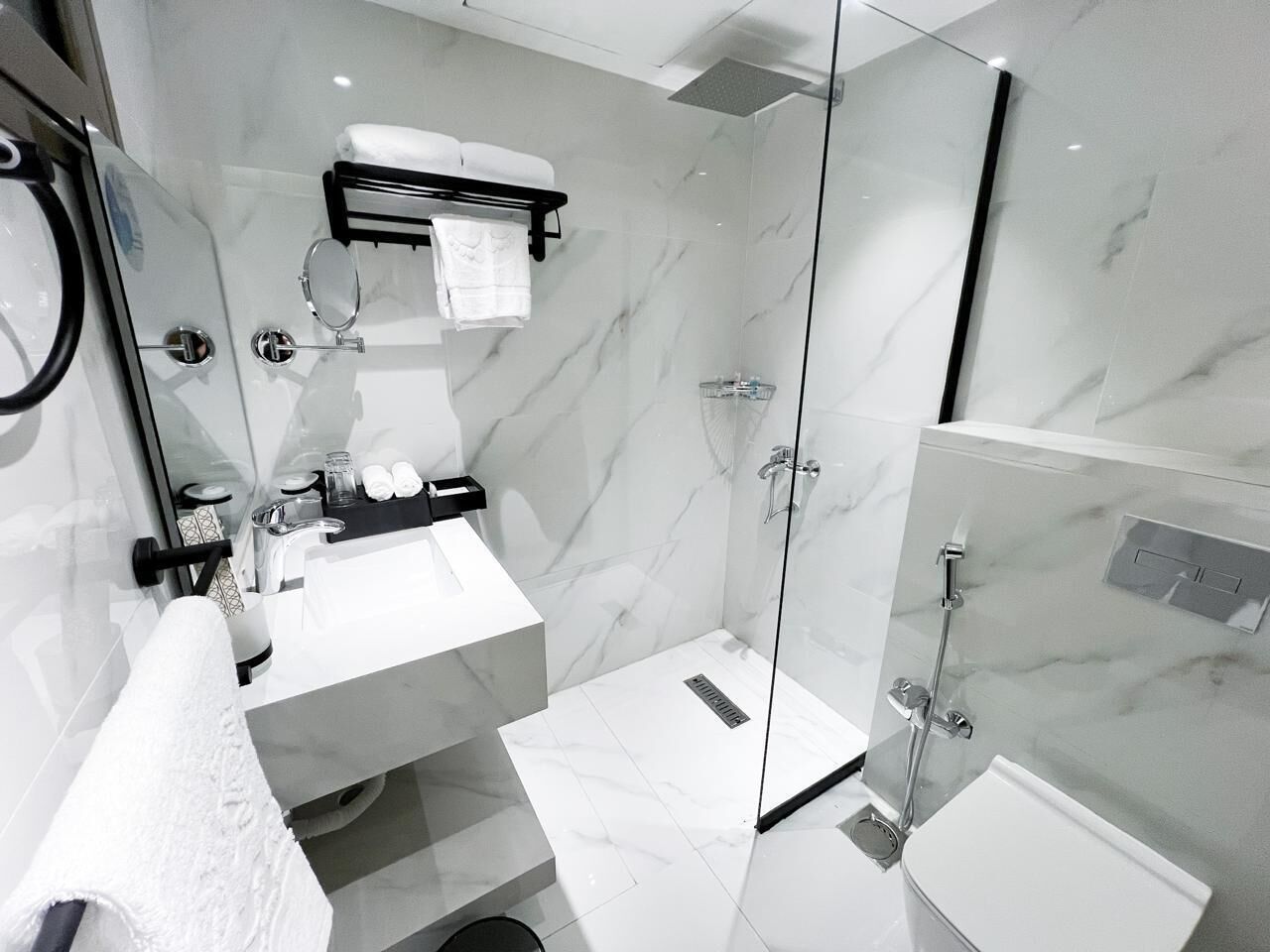 Une salle de bain moderne avec une douche à parois de verre, un lavabo blanc et un porte-serviettes.