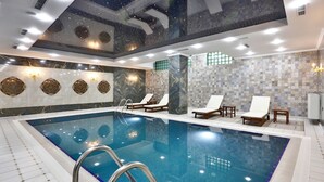 A large indoor swimming pool with a clear view of the ceiling, tiled walls, and lounge chairs. - ALERMO HOTEL & SPA  (Baku)