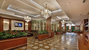 A hotel lobby with a patterned floor, chandeliers, a television, and potted plants. - ALERMO HOTEL & SPA  (Baku)