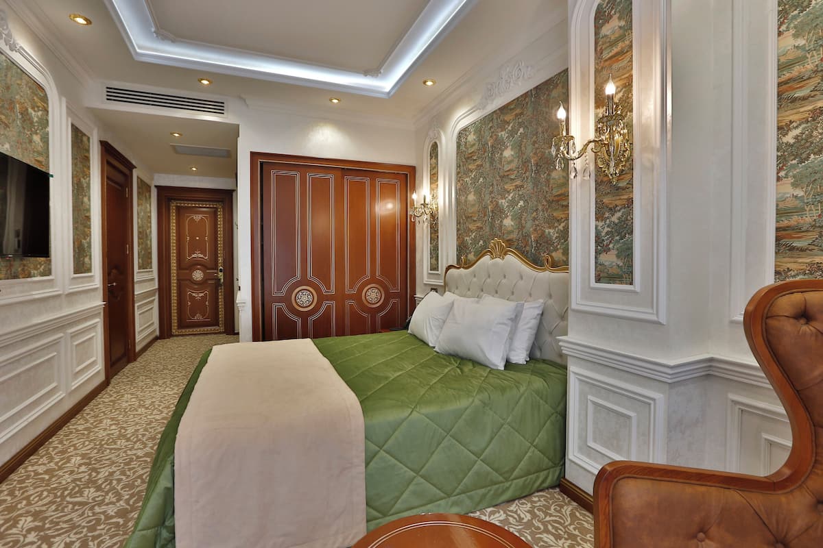 Una habitación de hotel con una cama grande, una silla de madera, un televisor y un adorno en la pared.