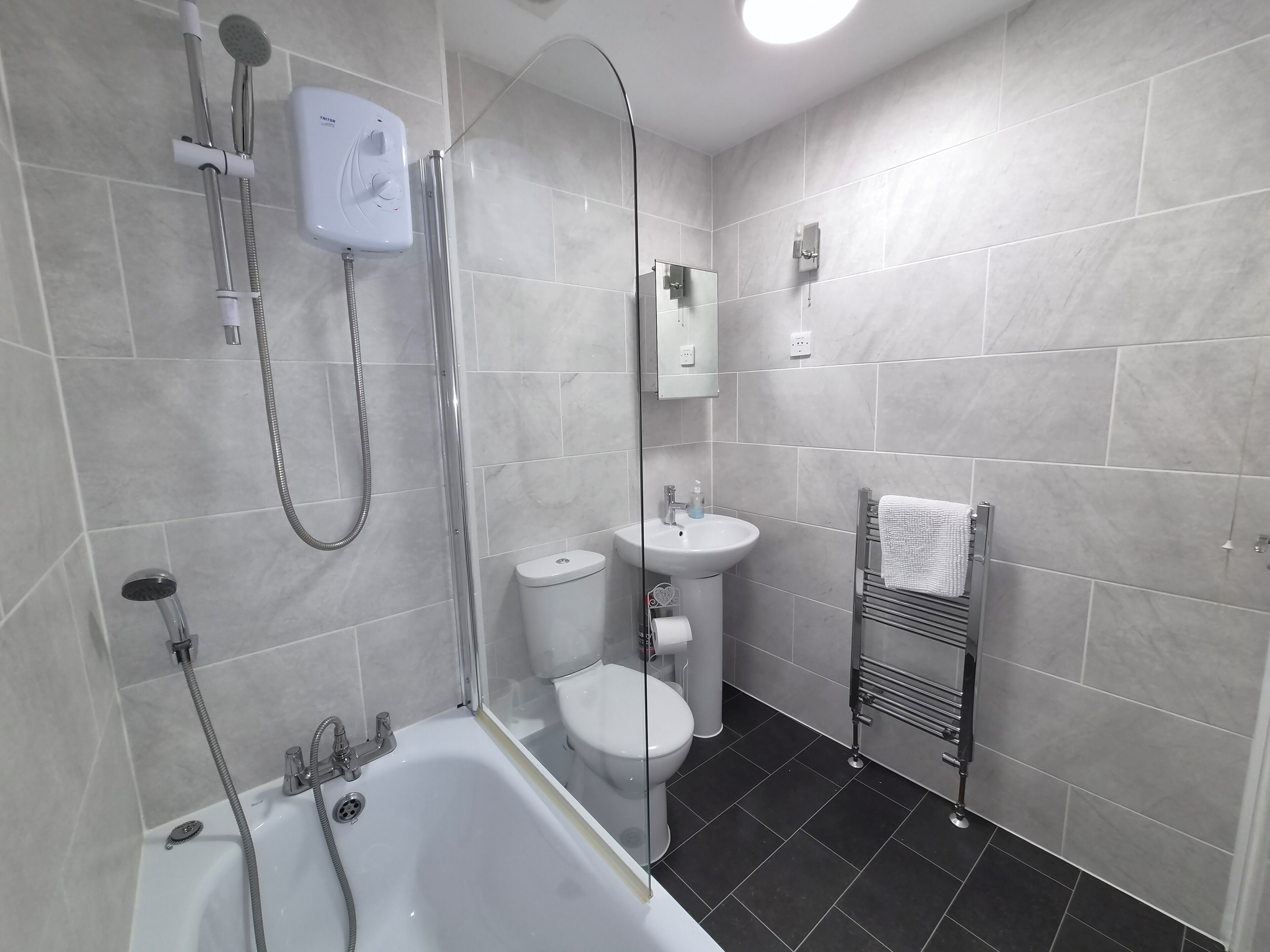 A modern bathroom with a bathtub, shower, toilet, and sink.