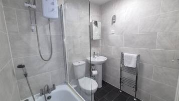 A modern bathroom with a bathtub, shower, toilet, and sink.
