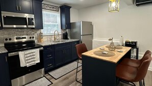 Une cuisine moderne avec des meubles de couleur sombre, des appareils électroménagers en acier inoxydable et une table à manger en bois.
