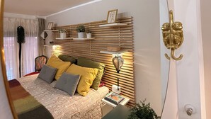 Un dormitorio con cama, mesita de noche, lámpara y un espejo que refleja la habitación.
