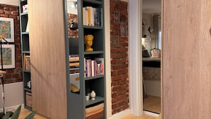 Una habitación con una estantería, pared de ladrillo y suelo de madera.