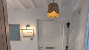 A hallway with a white door, a brown doormat, a framed picture on the wall, and a pendant light. - Stylish New Apartment in Central Seaview - 5 Star Comfort! (Seaview)