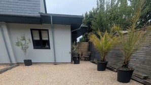 A gravel driveway leading to a house with a white exterior and a black window. There are several potted plants along the driveway. - Stylish New Apartment in Central Seaview - 5 Star Comfort! (Seaview)