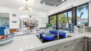 Una cucina moderna con isola centrale, mobili bianchi e un'ampia finestra che si affaccia sul verde.
