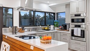 Una cucina moderna con un'isola grande, elettrodomestici in acciaio inossidabile e vista sull'esterno.