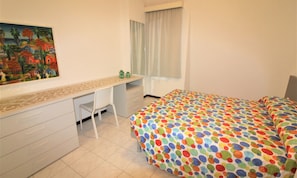 A bedroom with a bed, a desk, a chair, and a painting on the wall. - Duplex Only 150mt From the Beach (Lignano Sabbiadoro)