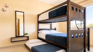 Een slaapkamer met een stapelbed, een spiegel, een kleine plant en een raam.