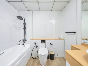 A modern bathroom with a white bathtub, a showerhead, a toilet, and a wooden vanity. - Luxury Waterfront View with Ain Dubai  (Dubai)