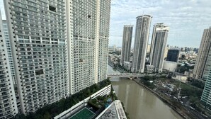 A high-rise building with a river in the foreground, surrounded by other high-rise buildings. - Acqua Novotel Suites w/ Rockwell View (Mandaluyong City)