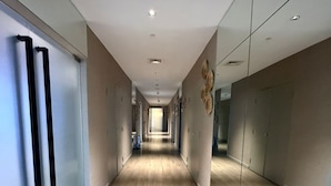 A long, narrow hallway with wooden flooring, recessed lighting, and mirrored walls. - Acqua Novotel Suites w/ Rockwell View (Mandaluyong City)