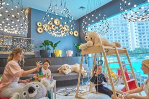 Ein modernes Wohnzimmer mit großem Fenster, einer Couch, einer Holzlade und einem Kind, das mit Bauklötzen spielt.