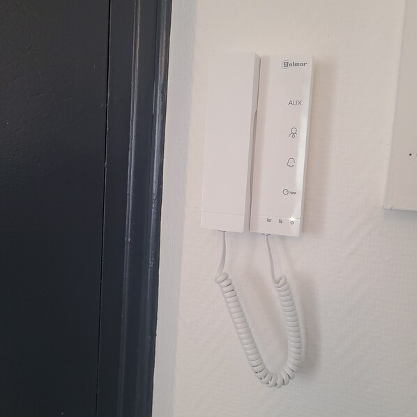 A white telephone mounted on a wall with a coiled cord. - Beautiful Brest Kérinou apartment refurbished (Brest)