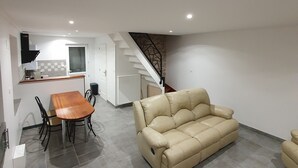 A spacious living area with a beige sofa, a wooden dining table with chairs, and a kitchen in the background. - Gite des 3 têtes de loups (Fumay)