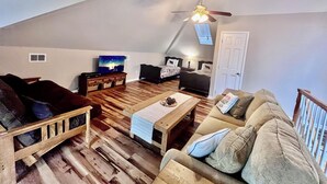 Ein gemütliches Wohnzimmer im Loft-Stil mit Holzboden, einer Couch, einem Couchtisch und einem Deckenventilator.