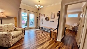 Ein geräumiges Wohnzimmer mit Holzboden, einem blumigen Sofa, einer Bank und einer Treppe zu einem anderen Raum.