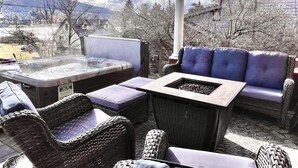 Eine Terrasss mit Korbmöbeln, einem Whirlpool und einem Kamin aus Stein.