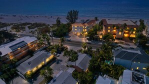 A coastal hotel with multiple buildings, a beach, and a sunset view.