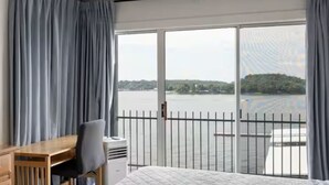 Une chambre d’hôtel avec une grande fenêtre, un lit, un bureau et une chaise.