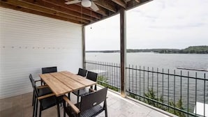 Un balcon abrité, doté d’une table et de chaises en bois, qui offre une vue sur une étendue d’eau.