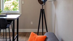 A modern living room with a gray sofa, a floor lamp, and a dining area with a table and chairs. - Cozy modern studio apartment in quiet Ridgefield with AC (Ridgefield)