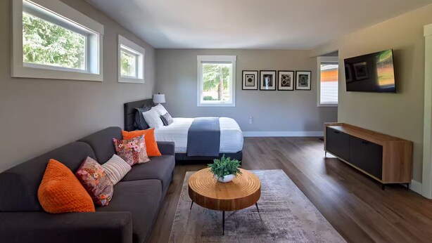 A modern living room with a large bed, a sofa, a coffee table, and a TV. - Cozy modern studio apartment in quiet Ridgefield with AC (Ridgefield)