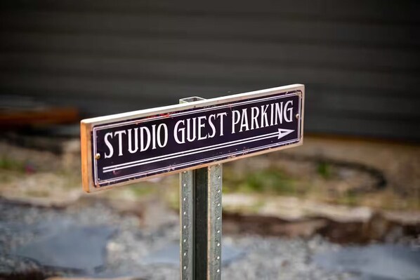 Schild mit der Aufschrift 'STUDIO GUEST PARKING' und einem Pfeil, der nach rechts zeigt.