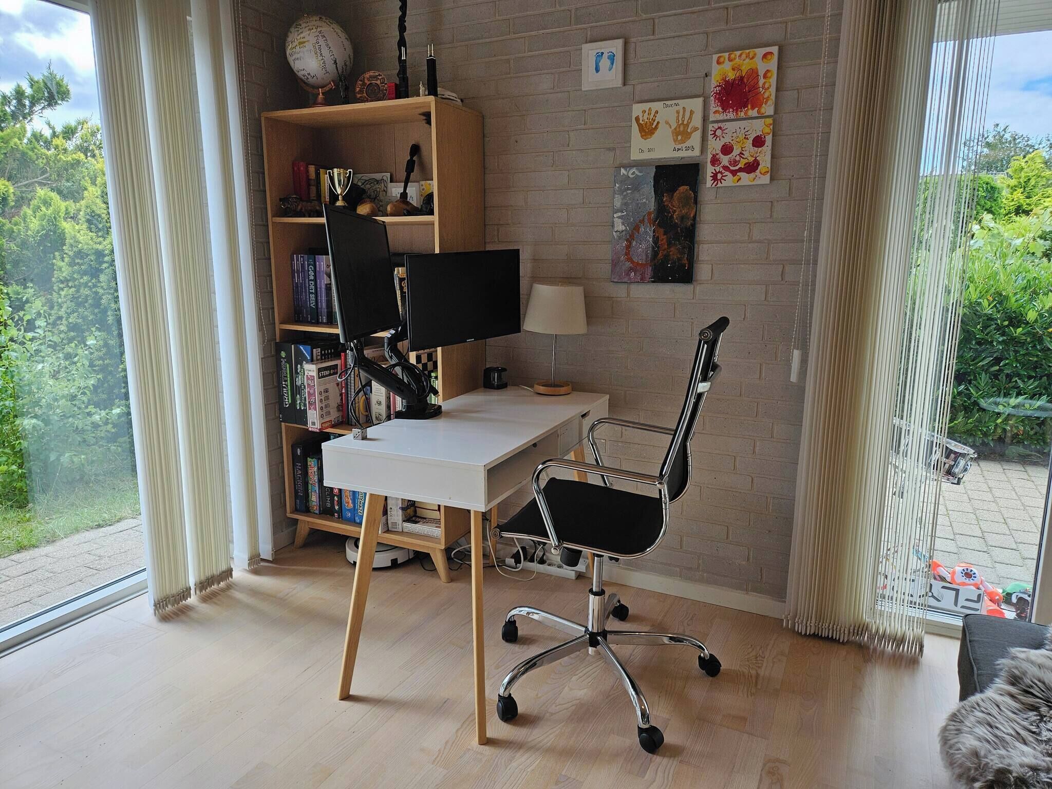A modern home office with a desk, computer, and bookshelf.
