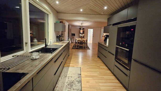 Een moderne keuken met een groot eiland, inbouwapparatuur en een eethoek op de achtergrond.