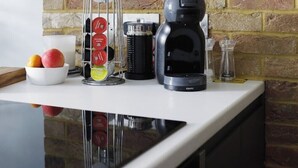 Eine Küchenarbeitsplatte mit einer Kaffeemaschine, einem Gewürzregal und einer Fruchtschale.