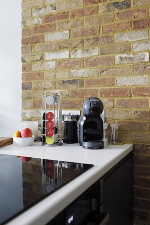 Eine Küchenarbeitsplatte mit einer Kaffeemaschine, einem Gewürzregal und einer Fruchtschale.