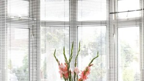 Ein modernes Zimmer mit einem runden Glastisch, zwei Stühlen und einer Vase mit Blumen.