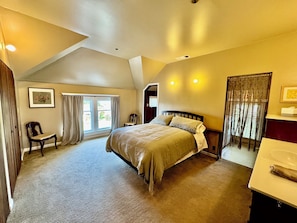 A bedroom with a bed, a chair, a desk, and a window with curtains.