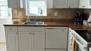 Een moderne keuken met witte kastjes, een vaatwasser, een kookplaat en een koffiezetapparaat.