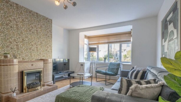 Una sala de estar moderna con chimenea, un sofá, un televisor y una ventana con persianas.