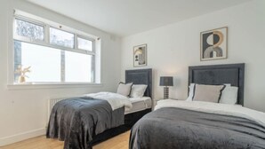 Un dormitorio con dos camas, una ventana y obras de arte en las paredes.