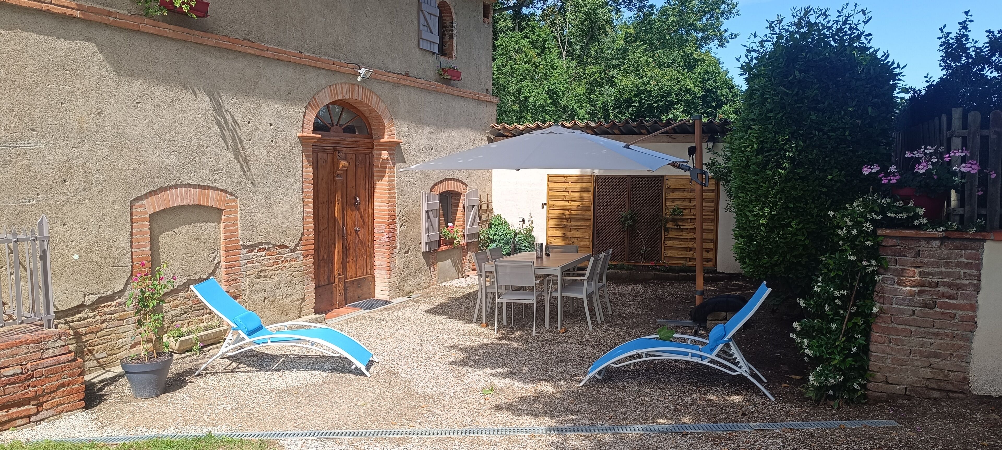 Un patio con mesa y sillas, una puerta de madera y una zona de estar cubierta.