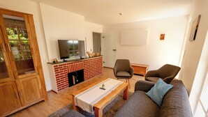 Un salón con sofá, sillones, una mesa de centro, televisor y chimenea de ladrillo.